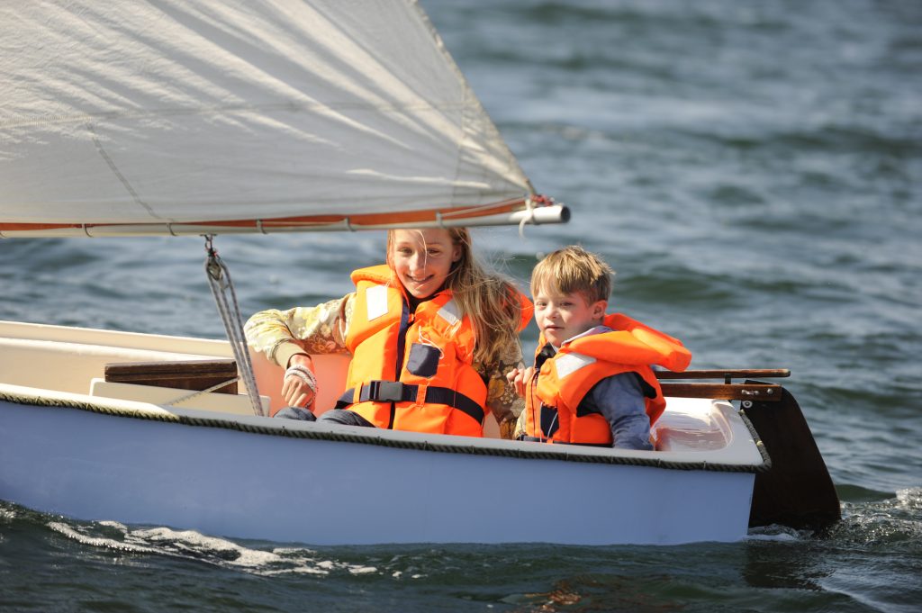 Sister and her brother with down syndrome are sailing in a small boat.